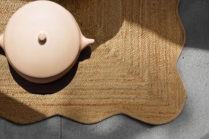 Pink teapot on a textured woven mat with a concrete floor background