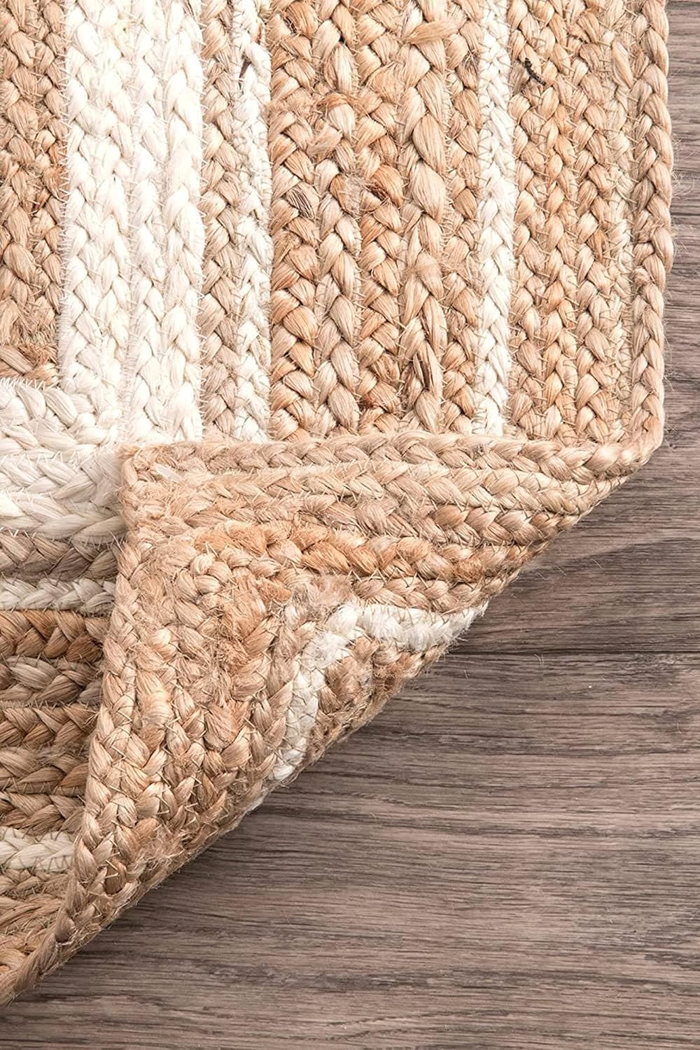 Close-up of a braided rug with beige and white stripes on a wooden floor.