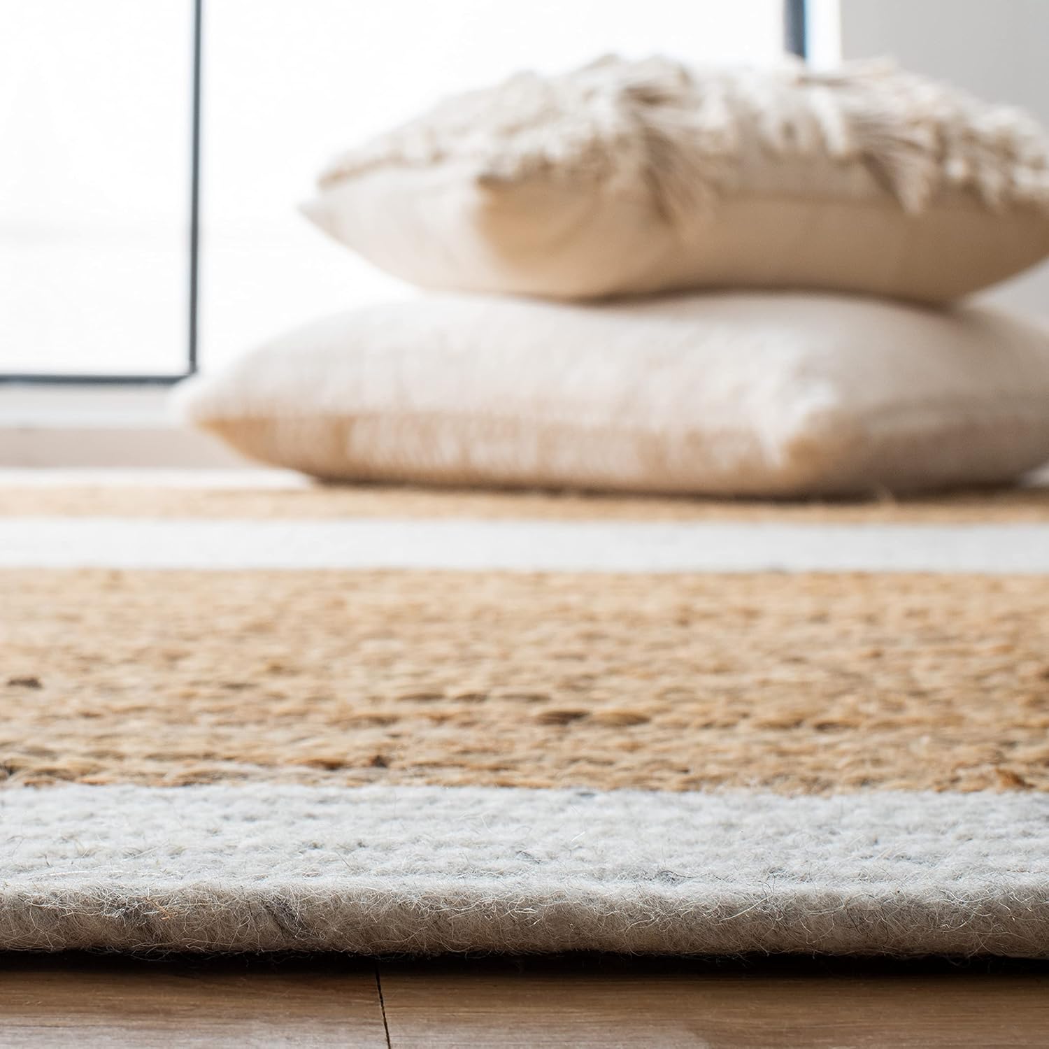 Natural jute area rug with white stripes, ideal for a cozy living space; soft and durable.